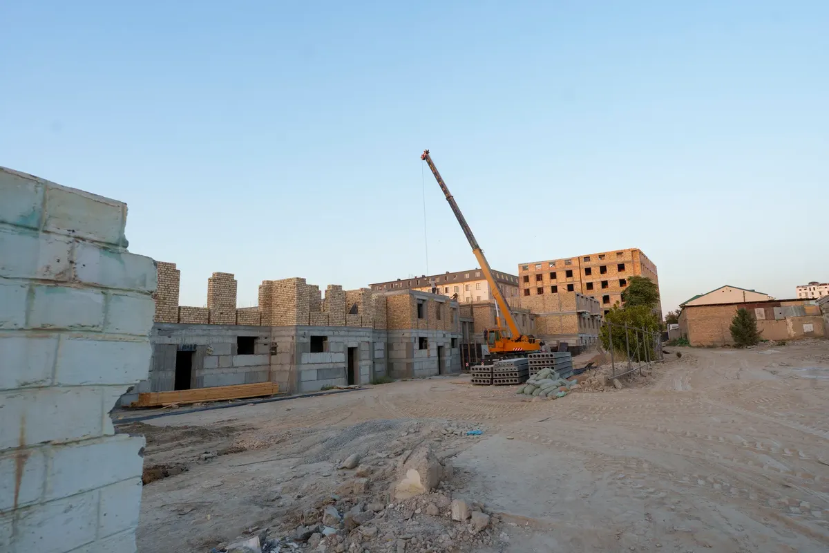 View of a construction site in Samarkand with buildings under development and a crane.