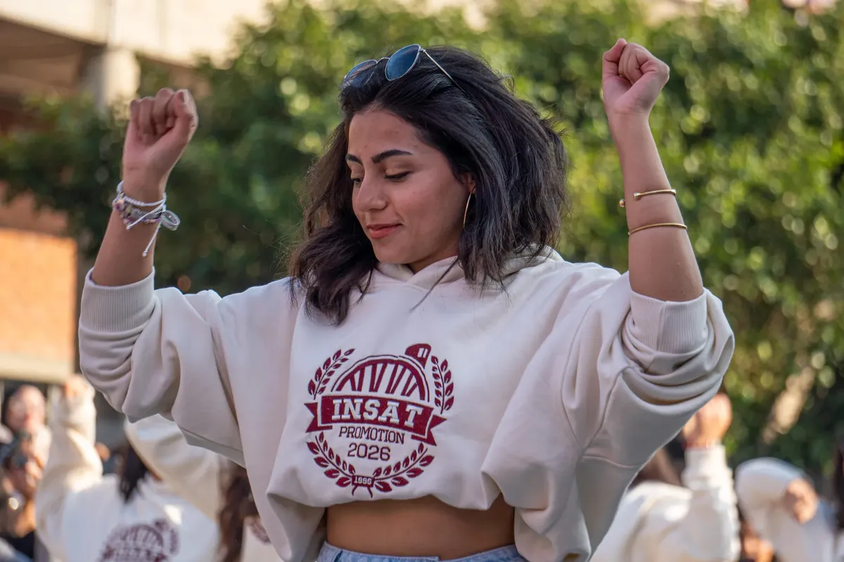 若い女性がホーリーフードを着て友達と一緒に屋外イベントで祝う。