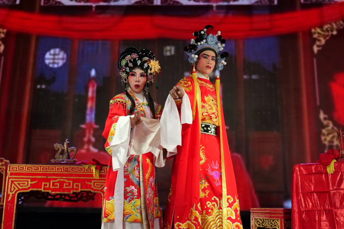 Elegant Chinese opera performers in vibrant costumes on stage, showcasing cultural beauty.
