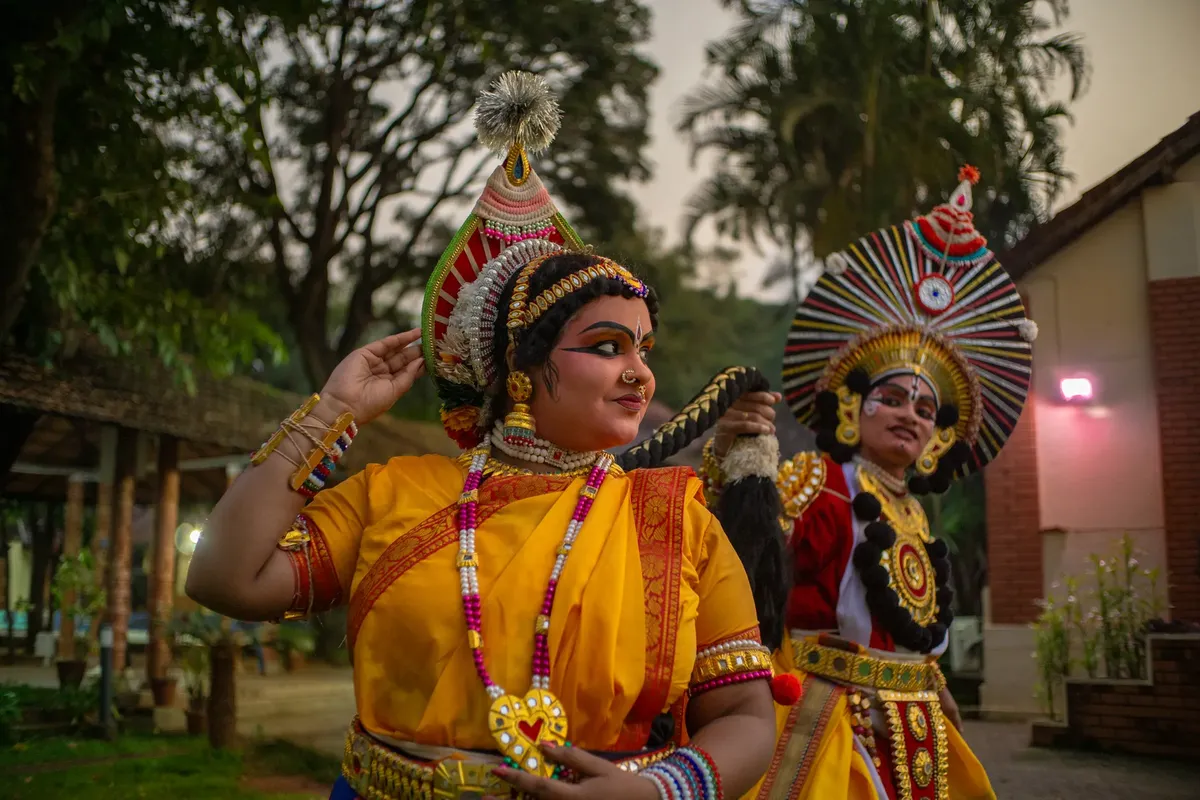 Two Yakshagana performers in traditional costumes and makeup, showcasing cultural heritage in an outdoor setting.