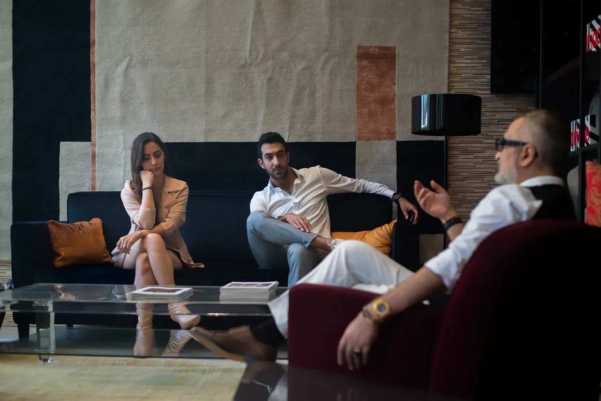 Three adults engaged in a thoughtful therapy session in a stylish Genoa interior.