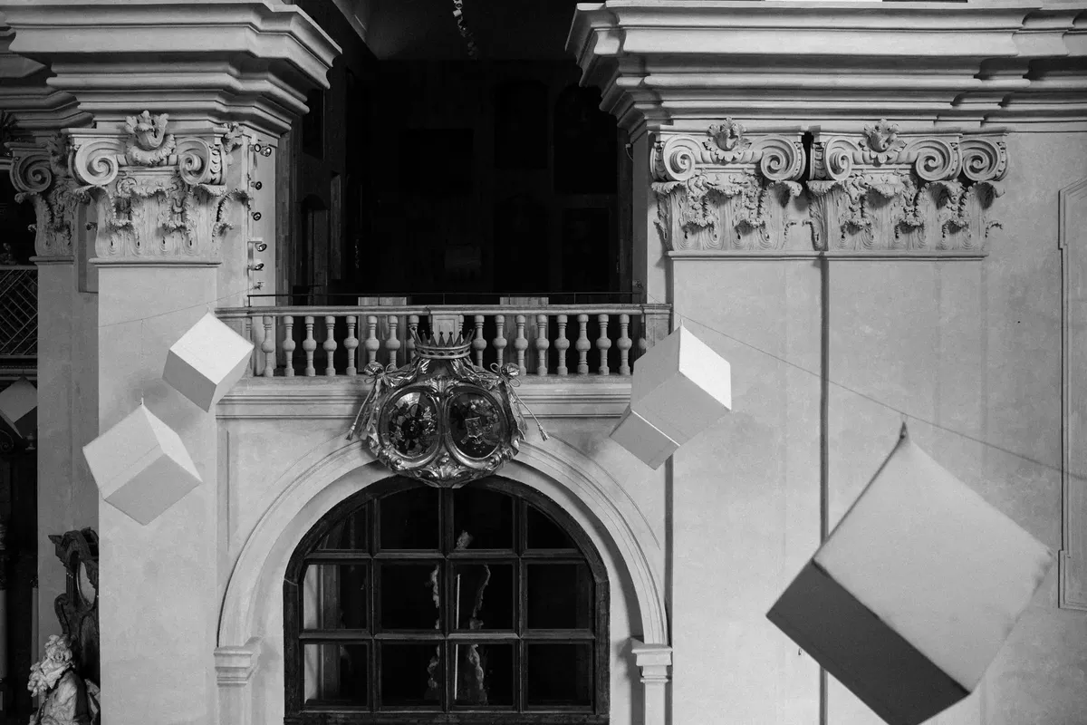 Classic architectural interior in black and white with suspended cubes creating a modern contrast.