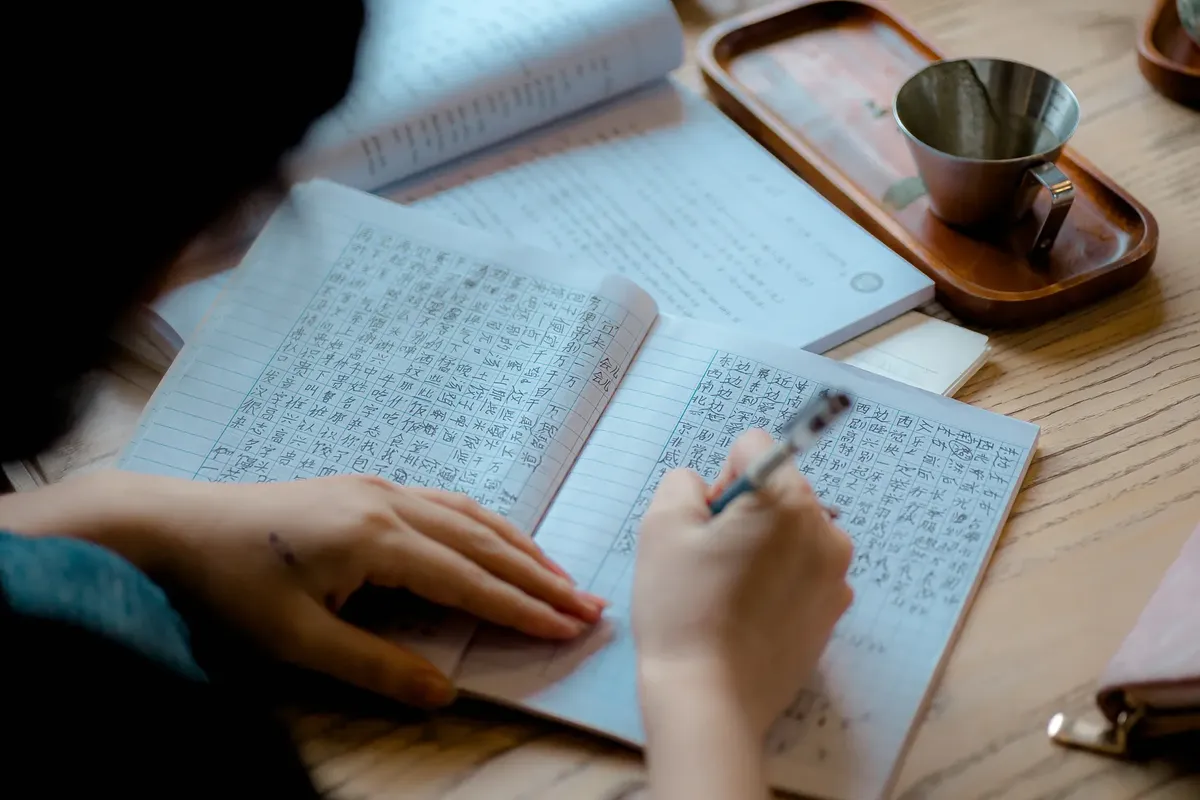 室内でアジアの文字を筆で書いている人物の特写。