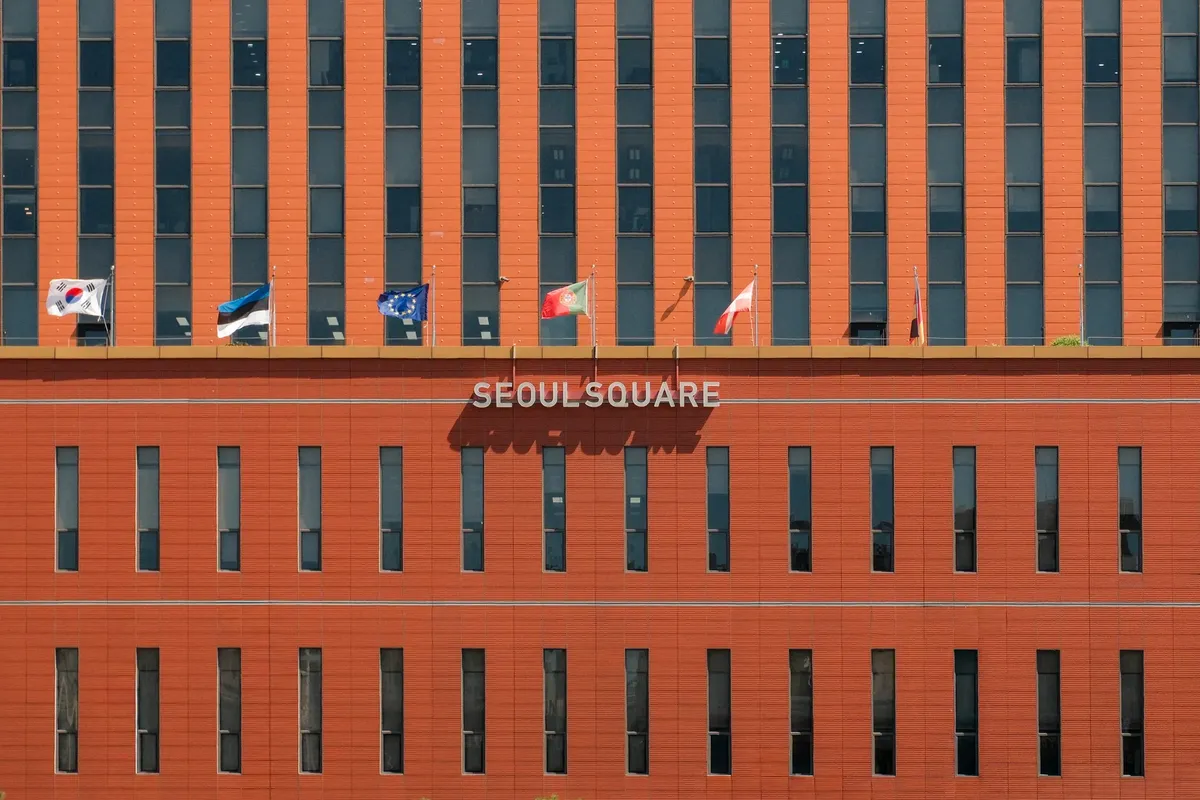 Red facade of Seoul Square with multiple international flags displayed.