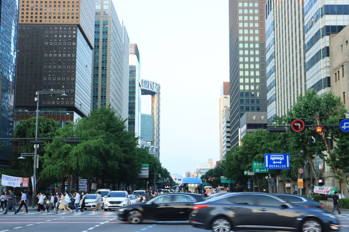 Street view of busy Seoul intersection, skyscrapers, traffic, and pedestrians.